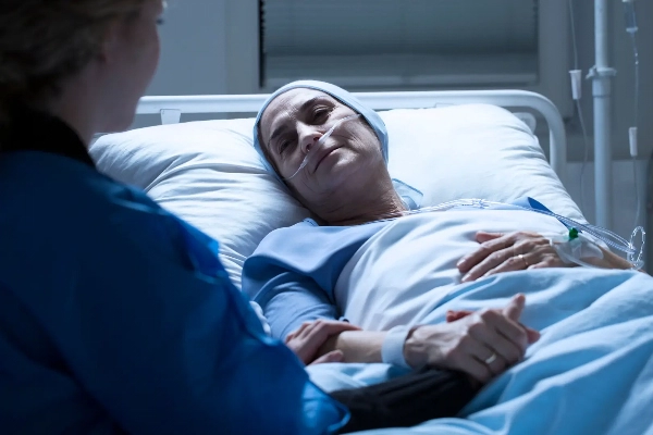 Nurse with her hand on the arm of an ill patient in bed