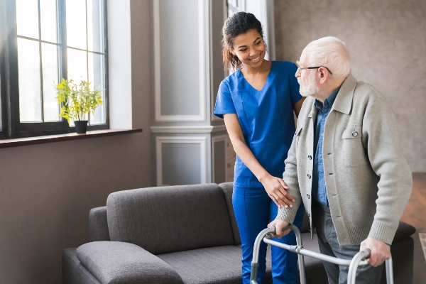 Nurse aiding elderly man with standing using his walker device